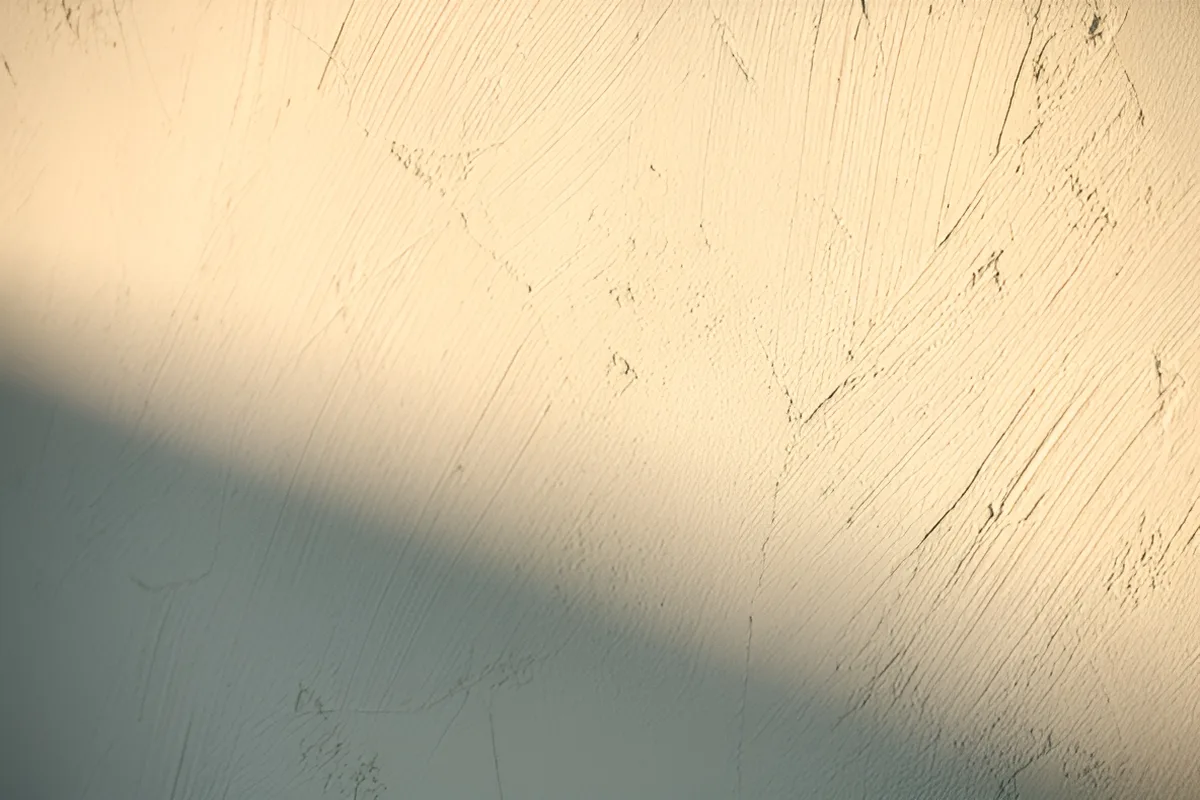 Close-up of hand-troweled lime plaster wall with soft raking light